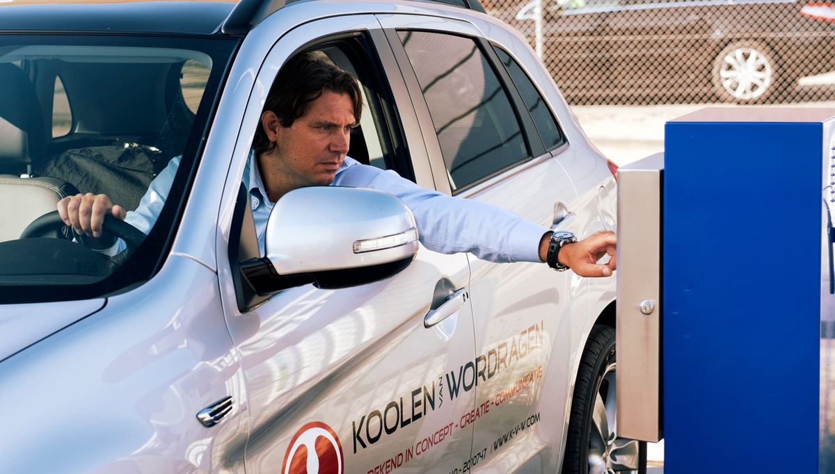 Man bedient het incheckterminal vanuit het voertuig op de parkeerplaats van Easy Airport Parking bij luchthaven Eindhoven (EIN)