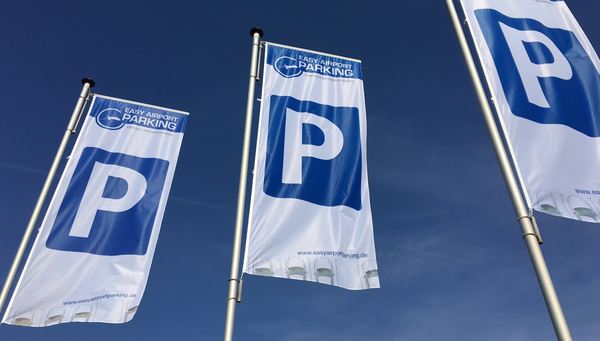 Three flags with Easy Airport Parking logo and parking symbol on the parking lot of Easy Airport Parking at Frankfurt-Hahn Airport (HHN)