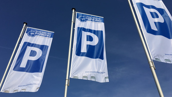 Three flags with Easy Airport Parking logo and parking symbol on the parking lot of Easy Airport Parking at Frankfurt-Hahn Airport (HHN)