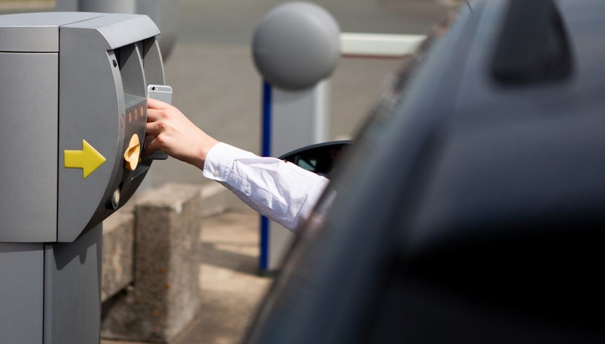 Fører tjekker ind med smartphone ved indkørslen til parkeringspladsen hos Easy Airport Parking i Frankfurt-Hahn Lufthavn (HHN)